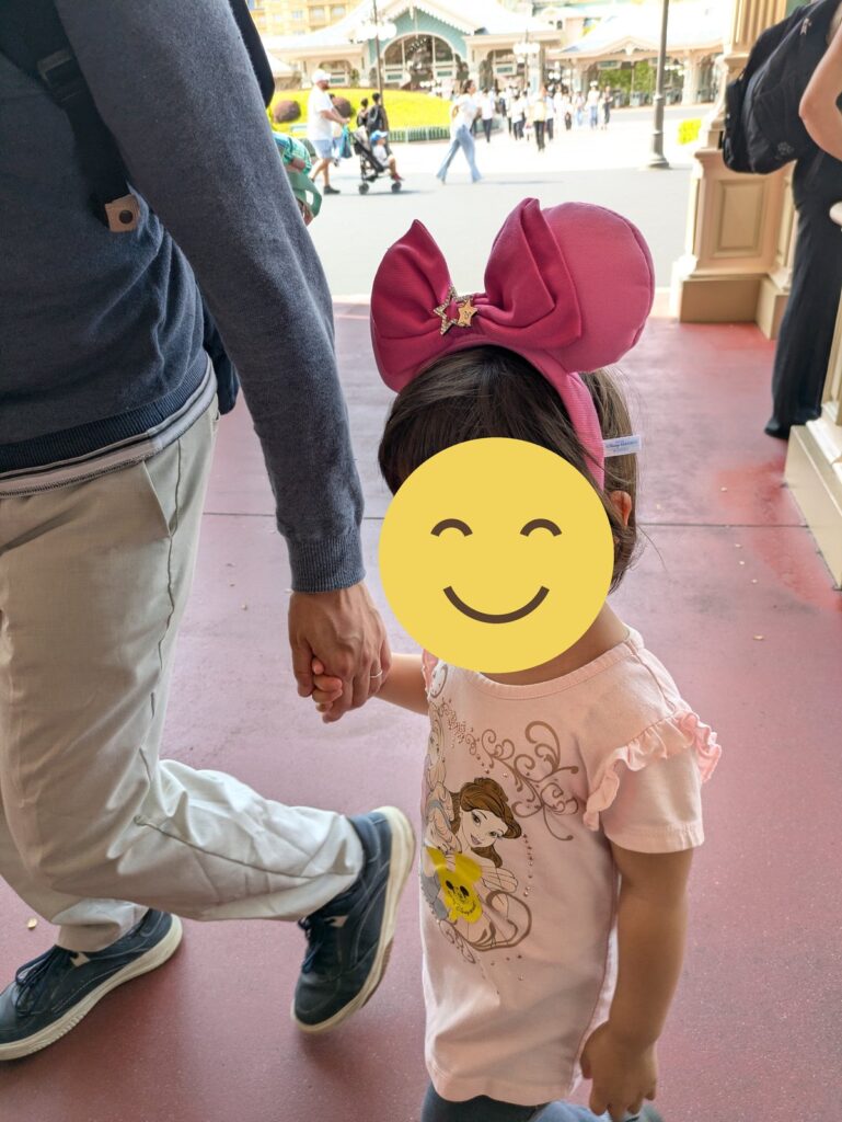ピンクのカチューシャをつけてパパと手をつなぐ娘